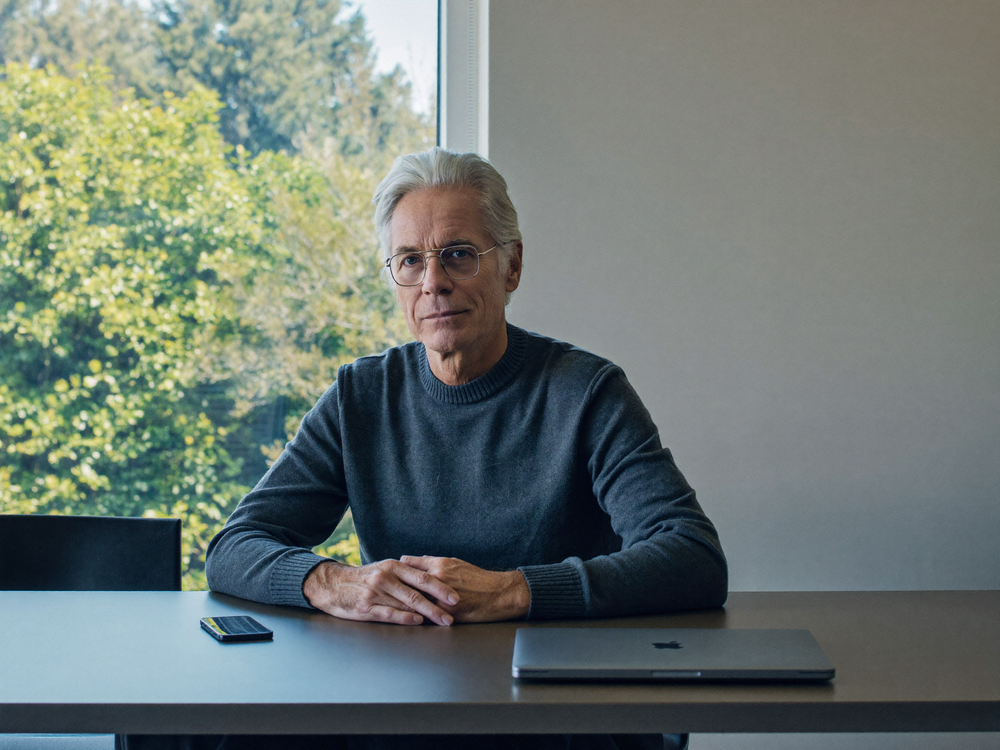 TORRAS creator story — a distinguished software creator seated at a minimalist desk with phone and laptop, cool-toned editorial portrait