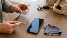A shopper preparing a screen protector beside a phone at home before daily use