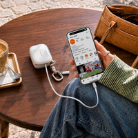 White TORRAS PackGo Cube 10K power bank charging an iPhone with its built-in cable on a cafe table