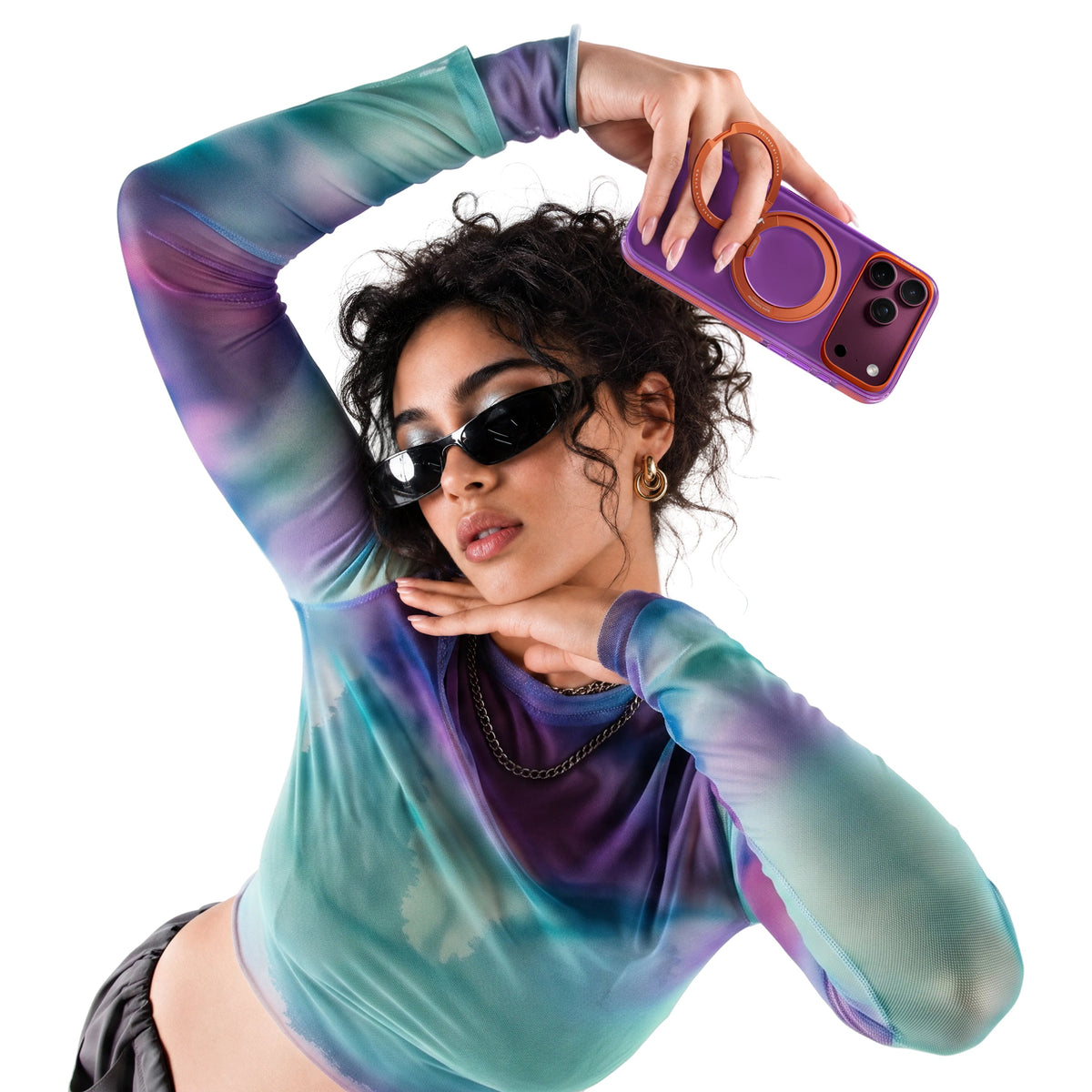 Woman in a tie-dye mesh top holding up an iPhone 18 Pro Max in the purple Hue case with an orange ring