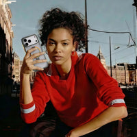 Woman in a red sweatshirt in a city square, holding an iPhone in the clear Football case with a red-yellow ring