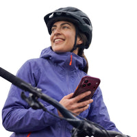 Cyclist in a purple jacket and helmet holding an iPhone 18 Pro in the plum Ostand Q3 Air case