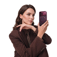 Woman in a brown suit raising an iPhone 18 Pro Max in the wine-purple Q3 Spin case, ring stand folded flat