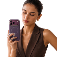 Woman in a brown vest holding an iPhone 18 Pro Max in the plum VegSkin leather case, ring stand folded out