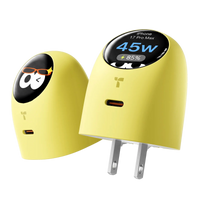 A yellow TORRAS FlashEye Dot charger, its round smart display showing the connected phone charging at 45W and 85 percent, beside a second unit showing an animated face and folding wall prongs