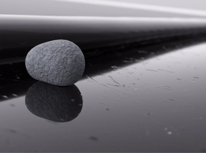 TORRAS Lab hinge durability test — stone resting on a scratched glossy black surface